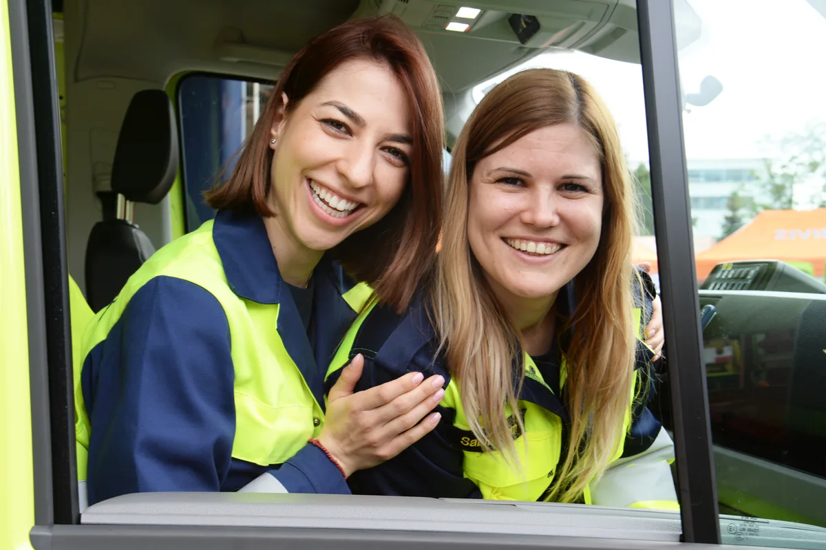 Zwei junge Frauen sitzen in einem Feuerwehrauto.